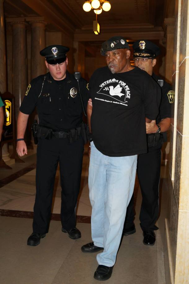 Will Williams arrested in WI Capitol 8.1.13. He is escorted to the elevator for processing after falling on the marble steps while handcuffed in police custody. Photo by Leslie Amsterdam